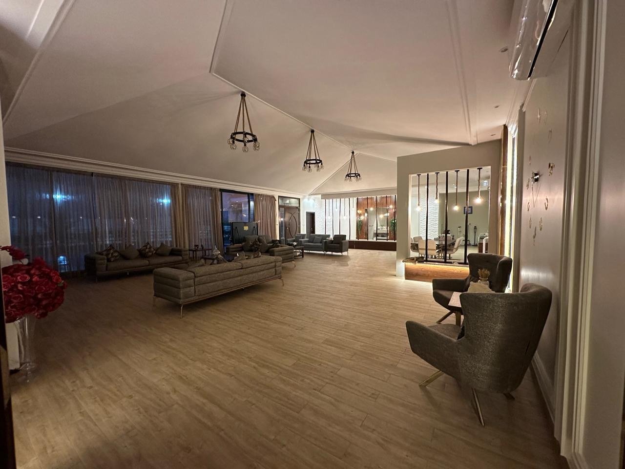 The residence at the heart of the estate — a pitched-ceiling hall long enough for a full tracking move, hung with rows of iron lanterns and opening into reception rooms on both sides.