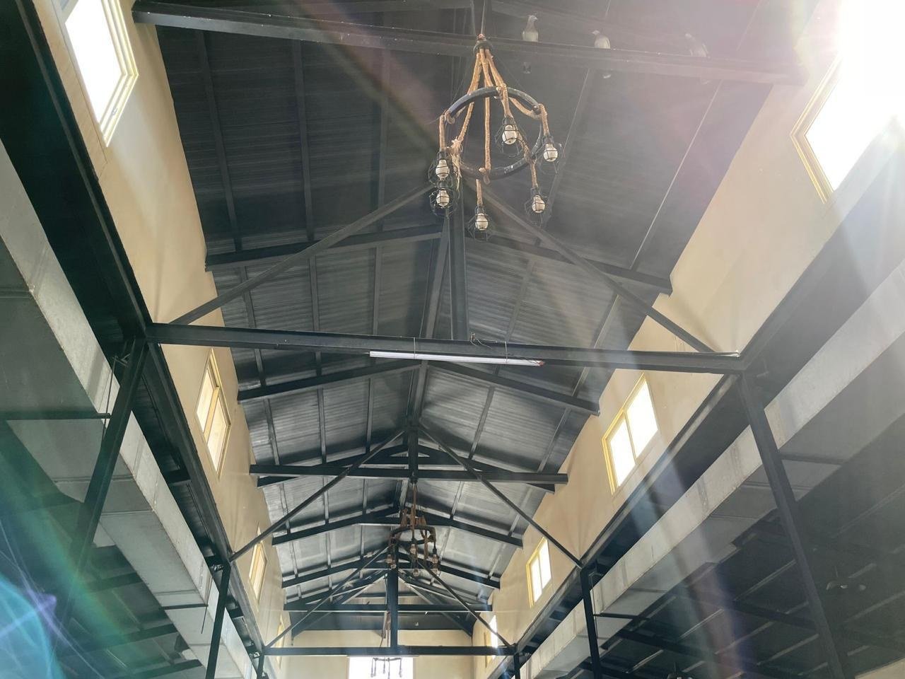 Black steel roof trusses and clerestory windows above the stable aisle.