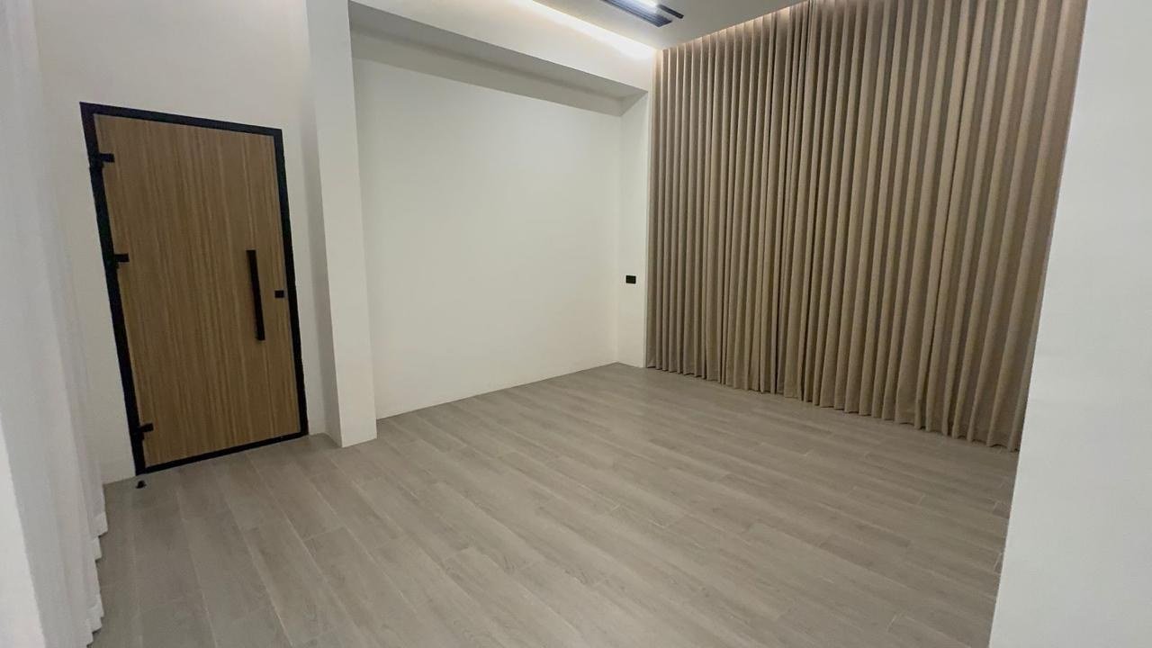 Timber pivot door set beside a fluted wood wall in a bare, clean-finished room.