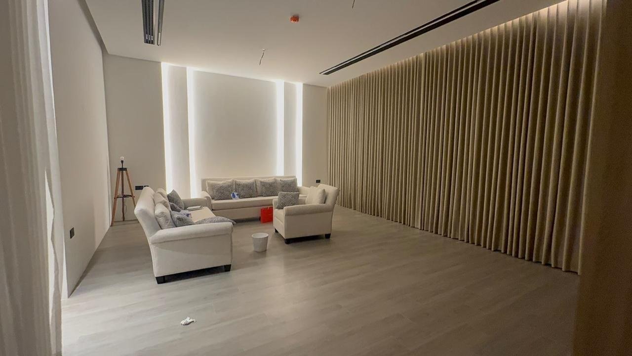 A contemporary villa in fluted timber and warm light — ribbed wood walls, concealed cove lighting, pale plank floors and rooms that run clean and empty.